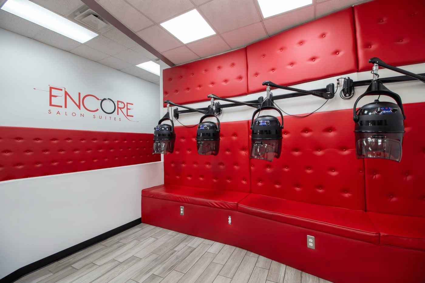 Dryer lounge with red tufted walls and four hooded dryers